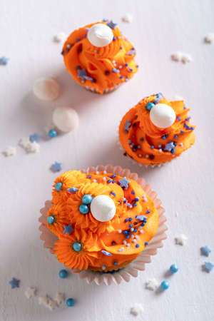 Homemade orange cupcakes made of peaches for fat thursday. Orange muffins with blue sprinkles.の写真素材