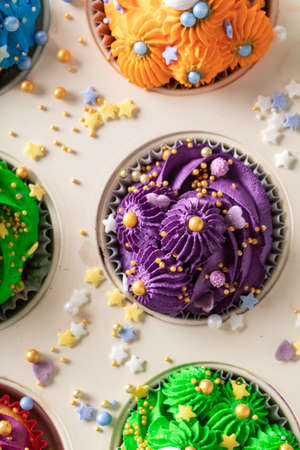 Sweet multicolored cupcakes with sprinkles and colored cream. Colored cupcakes with sprinkles and cream.の写真素材