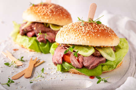 Tasty hamburger with lettuce, beef and pickles on white table.の写真素材