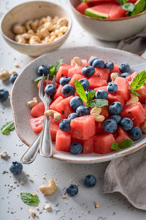Delicious watermelon salad with cashews, blueberries and mint leaves. Summer watermelon salad with berries and nutsの写真素材