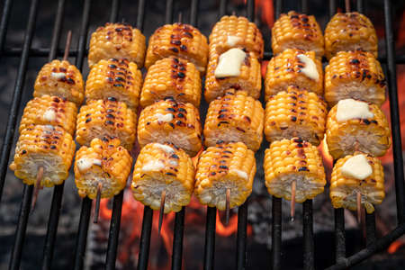 Hot corncob on grill on bonfire with flames. Corn cob roasted on a fire with butter.の写真素材