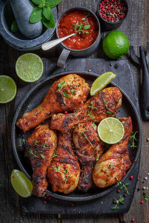 Hot roasted chicken leg served with lime and sauces. Grilled chicken leg with herbs and spicy spices.の写真素材