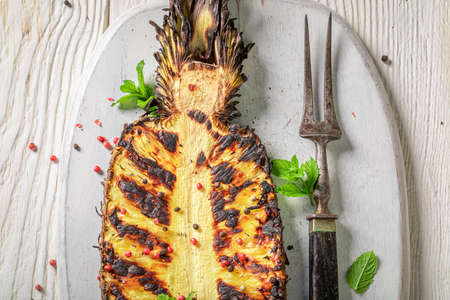 Homemade grilled pineapple with mint and red pepper. Grilled ananas on grate with fire.