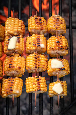 Hot corncob on grill with melting butter on fire. Grill with fire and baked corn.の写真素材