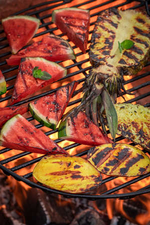 Sweet sear watermelon and pineapple in the summer garden. Grilled pineapple and watermelon roasted on fire.の写真素材