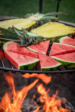 Sweet sear watermelon and pineapple on grill grate with fire. Roasted watermelon and pineapple on grill.の写真素材