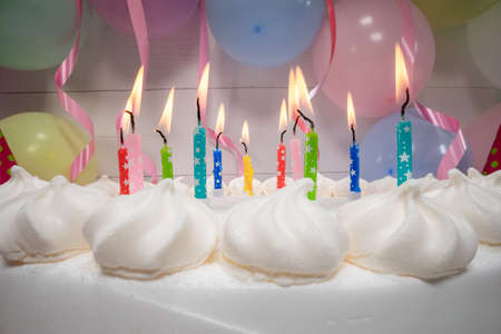 Candles on birthday cake on balloons and ribbons background. Candles on the birthday cake on party.の写真素材