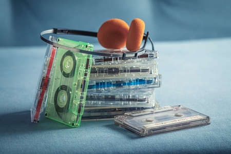 Old pile of cassette tapes with orange headphones. Cassette audio tapes with a red player and...