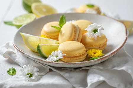Homemade and sour lemon macaroons with spring flowers on plate. Sour and sweet macaroons made of lemons.の写真素材