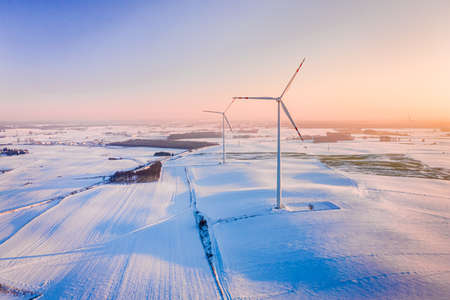 Alternative energy in winter. Wind turbine on snowy field in winter. Aerial view of nature in winter.の写真素材