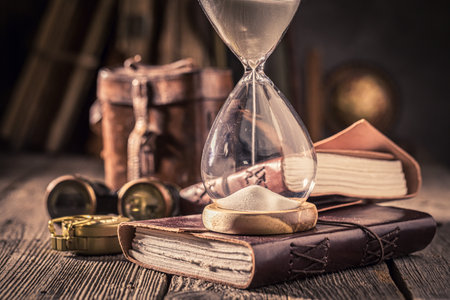 Old hourglass and journal as a journey memories concept. Symbol of passing time and memories.