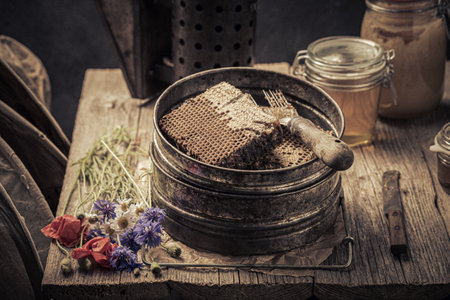 Rusty and old beekeeper tools with beekeeping knot full of honey. Ancient beekeeper workshop.の写真素材