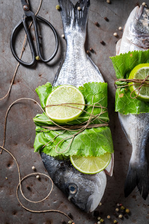 Seasoning freshl fish with horseradish leaves and lime. Preparations for grilling fish in herbs and spices.の写真素材