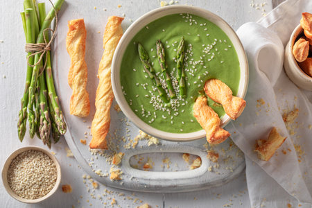 Healthy and fresh creamy asparagus soup served with grissini.. Veggie soup made of vegetables.