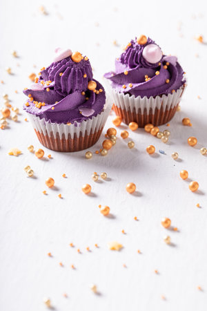 Sweet and tasty cupcakes as purple flower shape. Purple dessert with golden sprinkles.の写真素材