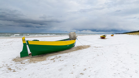 Fishing boats by Baltic sea on snowy beach in winter in Poland.の写真素材