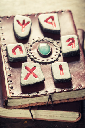 Closeup of black stones with red futhark sign on leather book as a mystical backgroundの写真素材