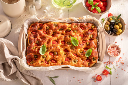 Homemade focaccia made of vegan and fresh ingredients. Traditional focaccia. Focaccia with olives and tomatoes.の写真素材