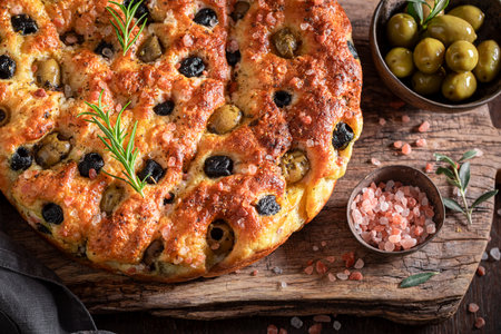 Homemade focaccia with olives and green herbs. Traditional focaccia. Focaccia made of simple ingredients.の写真素材