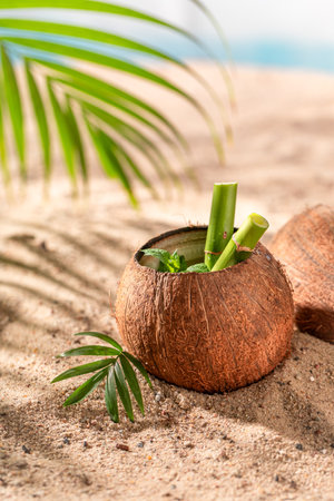 Delicious coconut milk in shell on a resort sandy beach. Drink served on an exotic beach.の写真素材