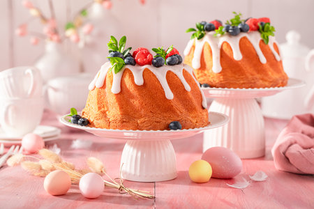 Sweet Easter ring cake with raspberries and blueberries. Easter spring background with flowers and...