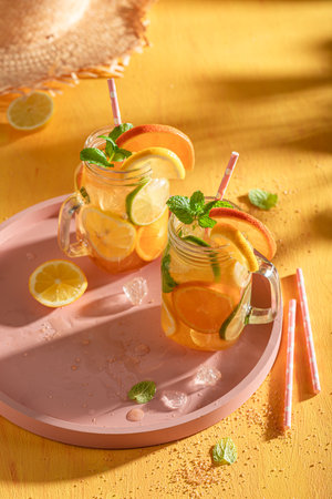 Homemade lemonade with ice on yellow wooden table. Mojito with mint and citrus.の写真素材