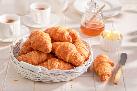Homemade and fresh french croissants served with coffee. Breakfast with coffee, honey and butter.の写真素材