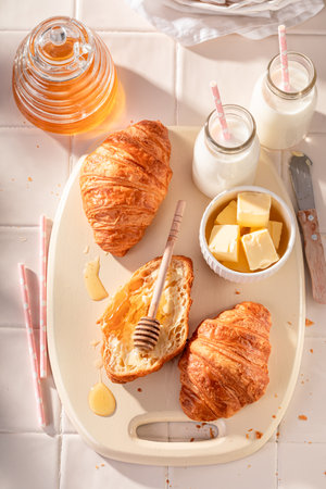 Sweet and golden french croissants served with milk. Breakfast with milk, honey and butter.の写真素材