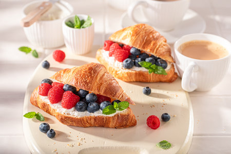 Golden and sweet french croissant with raspberries and blueberries. Croissants with spring and healthy ingredients.の写真素材