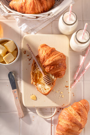 Homemade and hot french croissants made of puff pastry. Breakfast with milk, honey and butter.の写真素材