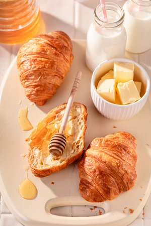 Homemade and hot french croissants served with milk. Breakfast with milk, honey and butter.の写真素材