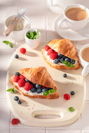 Golden and sweet french croissant in summer morning. Croissants as fresh sandwich with berries.の写真素材