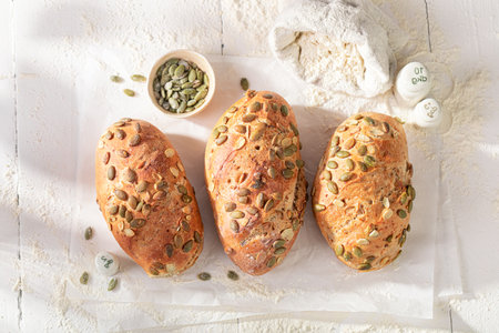 Homemade buns with pumpkin seeds on flour at the baker's place. Rolls baked in a bakery.