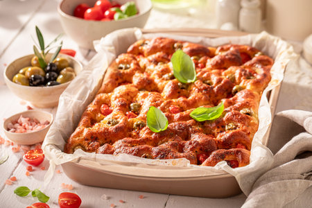 Homemade focaccia made of cherry tomatoes and basil. Classic Italian cuisine. Focaccia with tomatoes and olives.の写真素材