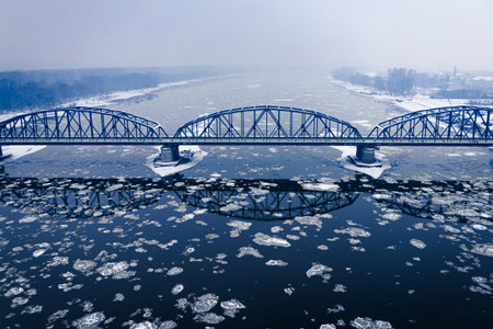 Snowy bridge and floes on river in winter. Aerial view of winter in Poland.の写真素材