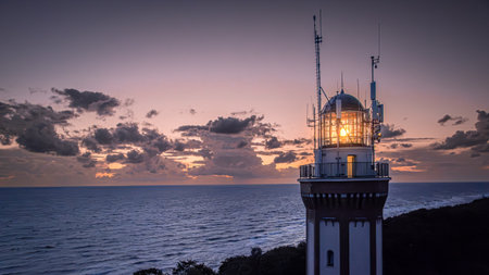 Aerial view of lighthouse after sunset by Baltic Sea with big waves in Poland after sunset.の写真素材