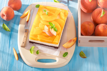 Tasty jelly peach cheesecake served on wooden blue table. Peach cheesecake with cocoa.の写真素材