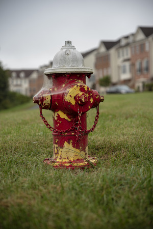 Fire hydrant in grass with houses in backgroundの写真素材