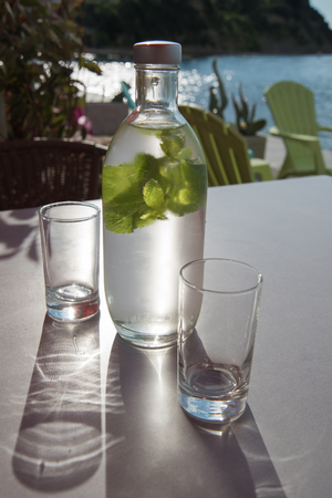 Bottle of cold mint water on a table with a sea on backgroundの写真素材