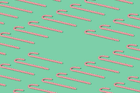 Creative pattern made with red Christmas candy canes. Minimal mint green New Year party background with copy space.の写真素材