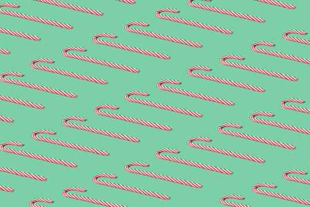 Creative pattern made with red Christmas candy canes. Minimal mint green New Year party background.の写真素材
