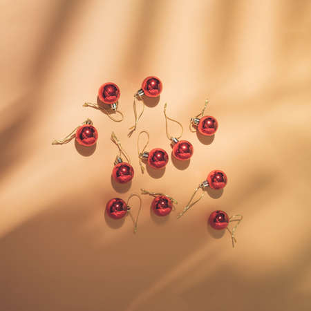 Top view of tropical leaf shadow and red Christmas baubles on sand color background. Trendy flat lay. Minimal New Year party concept. Vintage aesthetic.の写真素材
