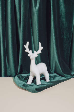 Creative vintage art direction. Minimal New Year or Christmas composition with with reindeer ornament on green and sand coloured background.の写真素材