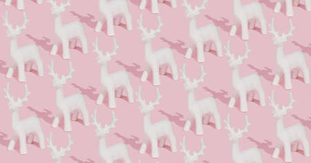 Creative pastel pink winter pattern made with white reindeer ornaments on pink background. Trendy Christmas composition.の写真素材