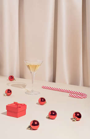 Minimal Christmas or New Year party composition with cocktail glass, baubles, candy cane and red gift box. Stylish and elegant vintage concept.の写真素材