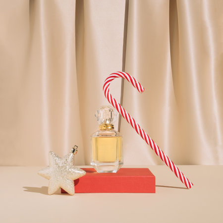 Minimal stylish holiday present composition with golden perfume , Christmas ornament and candy cane. Trendy vintage concept.の写真素材