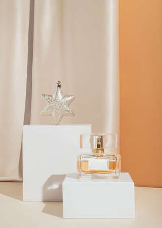 Minimal stylish holiday present composition with expensive perfume and golden Christmas ornament. Trendy luxury concept.の写真素材