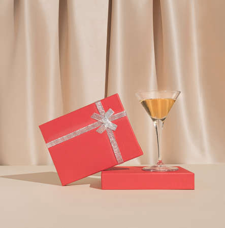 Minimal Christmas or New Year party composition with cocktail glass and red gift box. Stylish vintage concept.の写真素材