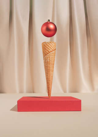 Minimal vintage holiday decoration composition with red Christmas bauble ornament and ice cream cone. Trendy elegant concept.の写真素材