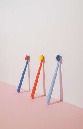 Trendy minimal composition with three colorful toothbrushes on pastel pink background. Modern aesthetic.の写真素材